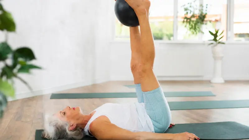 Aluna 60+ treinando equilíbrio e postura no estúdio de Pilates
